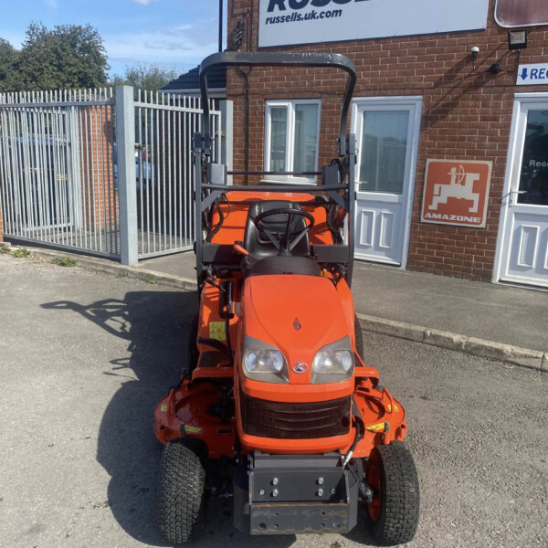 Front view of an orange riding lawn mower parked in a driveway in front of a brick building with a Russell’s sign above the door.