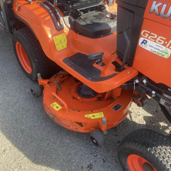 Close-up of an orange riding lawn mower deck with a black seat and pedals visible underneath the seat area