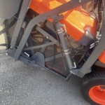 Close-up of an orange safety bag or tarp within a heavy machine frame, with hydraulic arms and metal supports visible.