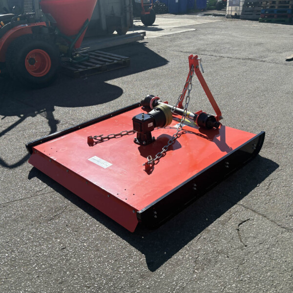 Red industrial platform with chains and lifting hardware in a yard, surrounded by machinery and pallets in the background.