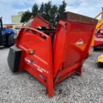 Red KUHN Primor 2060 bale wrapper on a gravel lot, with other farm equipment in the background.