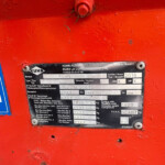 Close-up of a red machine body with a metal identification plate showing brand KUHN and specs, including year 2016 and serial numbers.