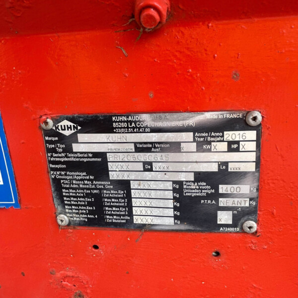 Close-up of a red machine body with a metal identification plate showing brand KUHN and specs, including year 2016 and serial numbers.