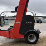 Red KUHN SW 4014 agricultural implement at a construction site, close-up of the machine's red frame and black housing with wheels visible.