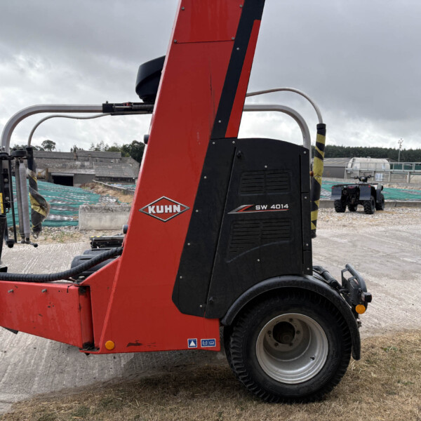 Red KUHN SW 4014 agricultural implement at a construction site, close-up of the machine's red frame and black housing with wheels visible.