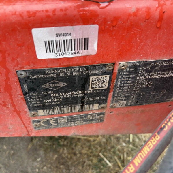 Close-up of a red agricultural machine with a white barcode sticker reading SW4014 and a black metal plate from KUHN-GELDROP B.V. attached.