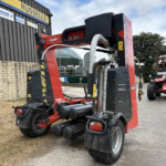 Red KUHN SW 4014 agricultural machine parked beside a dark building with a yellow Russell’s sign in the background.