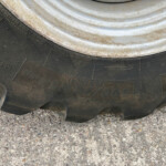 Close-up of a dirty tire sidewall with worn tread resting on a gravel surface.