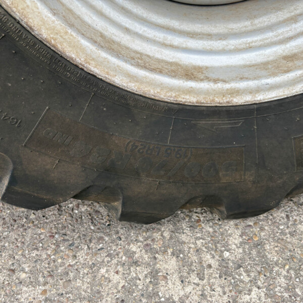 Close-up of a dirty tire sidewall with worn tread resting on a gravel surface.