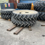 Stacks of large tractor tires on wooden pallets in an outdoor industrial yard.
