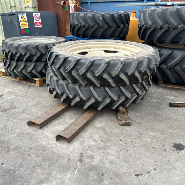 Stacks of large tractor tires on wooden pallets in an outdoor industrial yard.