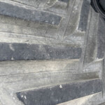 Close-up of stacked black rubber tires with deep grooves and a dusty surface.
