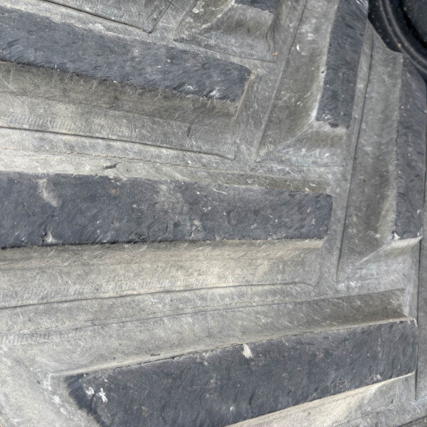 Close-up of stacked black rubber tires with deep grooves and a dusty surface.