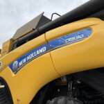 Close-up of a bright yellow New Holland CR8.90 machine with its blue brand decal visible on the side panel.