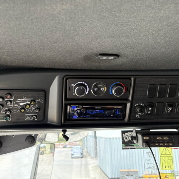 Interior truck cab dashboard with climate control dials, switches, and a stereo unit visible below the overhead panel.