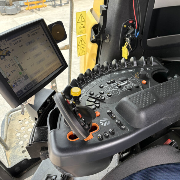 Cabin of heavy machinery with a mounted touchscreen display, keyboard-like controls, and key ring near the door frame