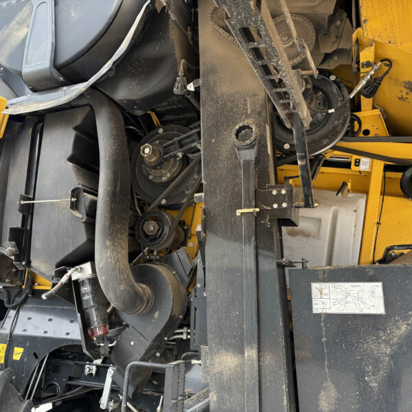 Close-up view of dusty industrial machinery with belts, pulleys, and a yellow frame in the background?
