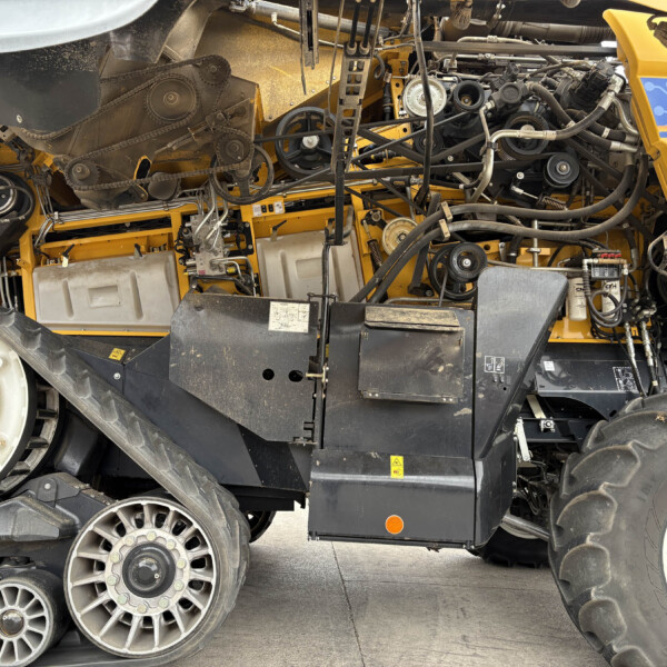 Exposed belts, pulleys, and hoses inside the yellow agricultural combine harvester.