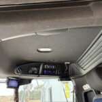 Interior view of a truck cabin showing the dashboard with gauges, radio, and climate controls, plus overhead panel and sun visor across the top.