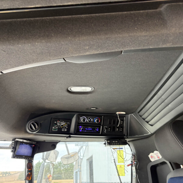 Interior view of a truck cabin showing the dashboard with gauges, radio, and climate controls, plus overhead panel and sun visor across the top.