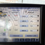 Monitor screen labeled 'Service Setup' showing Engine Hours 1253.52 h and Threshing Hours 1024.60 h with a yellow combine image on the left.