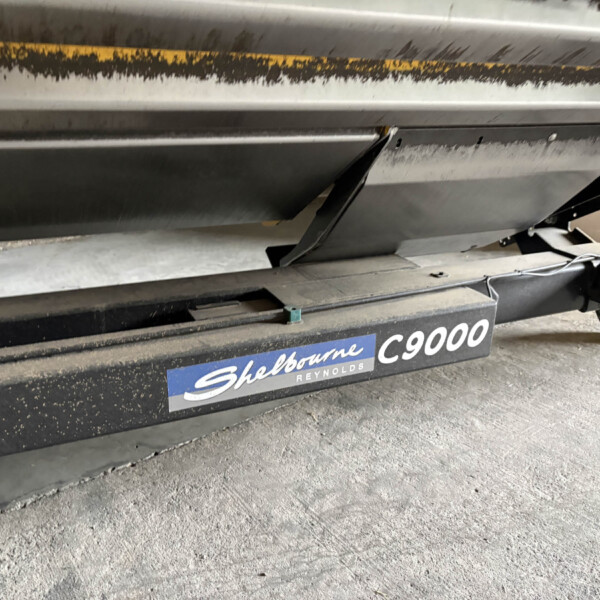 Close-up of industrial equipment underside showing a black-and-yellow wear stripe and a Shelbourne Reynolds C9000 label on the base.