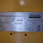 Metal identification plate on yellow machinery showing CNH Industrial Polska Sp. z o.o. and New Holland Agriculture branding, Poland origin info.