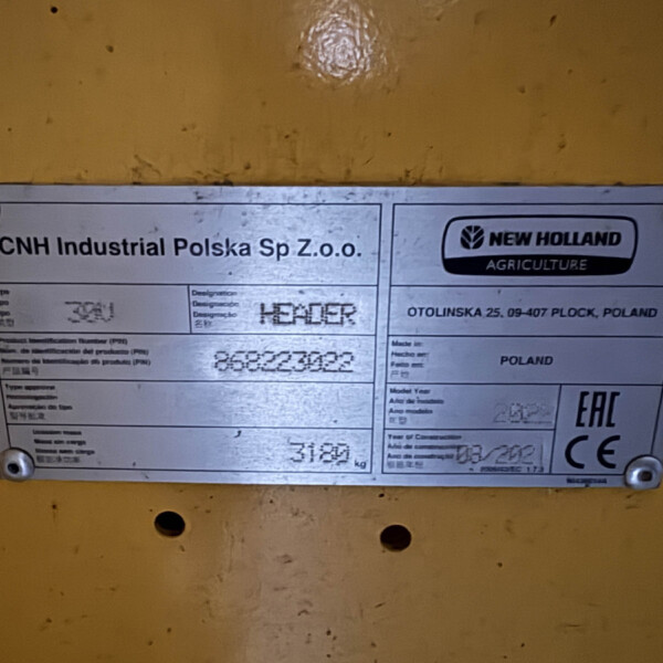 Metal identification plate on yellow machinery showing CNH Industrial Polska Sp. z o.o. and New Holland Agriculture branding, Poland origin info.