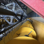 Industrial machinery with metal frames and yellow components, viewed from a tilted angle in a workshop setting