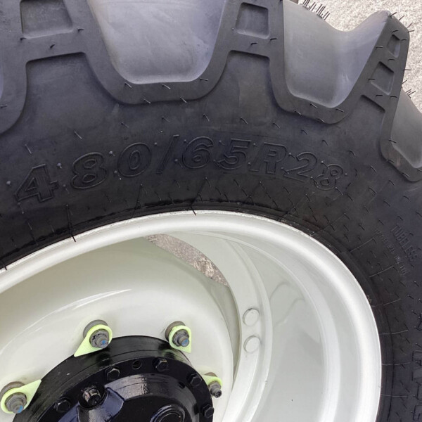 Close-up of a large off-road tire mounted on a metal wheel with lime-green lug nuts and a black hub area.