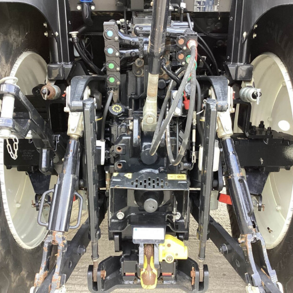 Close-up view of a truck's hitch and hydraulic system between the rear wheels of a tractor-trailer.