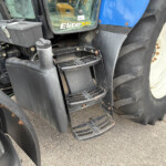 Close-up of a blue tractor with black steps and a large treaded tire, showing the Elite logo on the cab window.