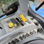 Interior of a dusty tractor cabin showing yellow control levers and dashboard buttons