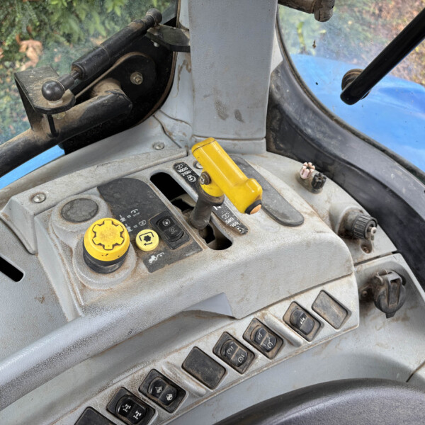 Interior of a dusty tractor cabin showing yellow control levers and dashboard buttons