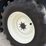 Close-up of a large tractor tire with a white rim and dirt on the treads.