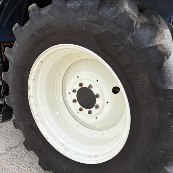 Close-up of a large tractor tire with a white rim and dirt on the treads.