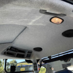 Interior roof of a truck cab featuring a warm overhead light and control panel on the ceiling