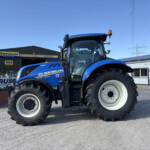 Blue New Holland tractor parked outside a farm equipment shop with Russell's and New Holland Agriculture signage under a clear blue sky.