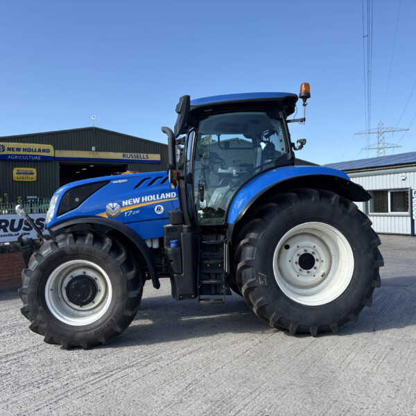 Blue New Holland tractor parked outside a farm equipment shop with Russell's and New Holland Agriculture signage under a clear blue sky.