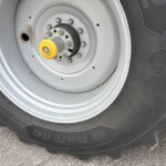 Close-up of a tractor wheel hub with a yellow valve cap and rusted lug nuts on a large tire hub