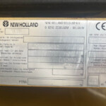 Metal identification plate on a yellow surface showing the New Holland logo and model TF78 with weight fields.