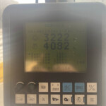 Close-up of a machine control panel LCD showing large numbers 3222 and 4082 with rows of labeled function buttons below (MEM, CAL, SERVICE).