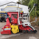 Colorful farming equipment on display outside a shop, with Pöttinger branding visible.**