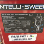 Close-up of a red machine panel featuring a black Intelli-Sweep label and a maintenance/parts sticker underneath for service instructions.