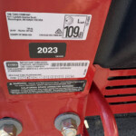 Close-up of a red Toro machine frame showing an identification/emissions label and large bolts.