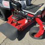 Red riding lawn mower deck with black control levers and foot platform, Toro 2000 HDX branding visible on side panel