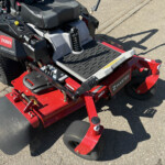 Close-up of a Toro Z-Master riding mower seat and control panel with red chassis and black foot platform.