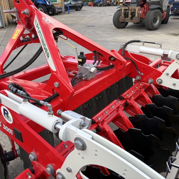 Red Terradisc 3001 soil cultivator with hydraulic hoses and silver cylinders, shown outdoors at a farm equipment site.