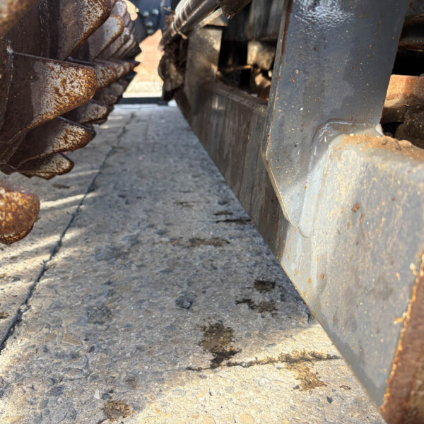 Close-up of rusty metal gears and a weathered gray frame on a rough concrete surface.