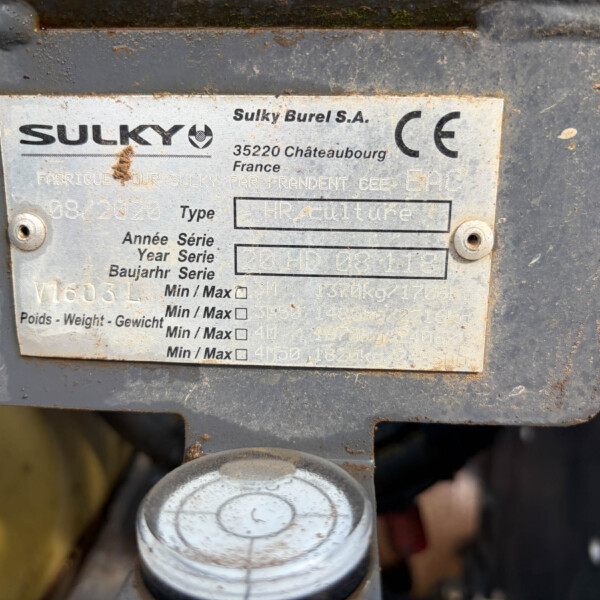 Close-up of a weathered metal identification plate on agricultural machinery showing the Sulky logo, CE mark, and blank fields for type and year.